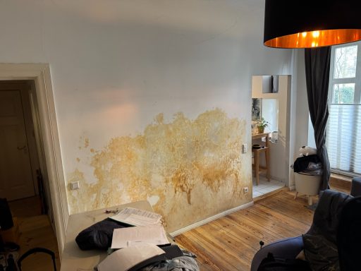 Wand mit sichtbaren Wasserschäden und Abblätterungen.